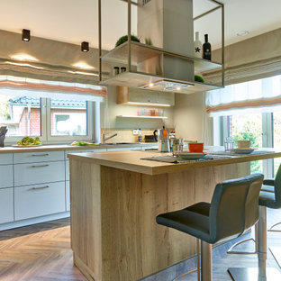 Zweizeilige, Mittelgroße Moderne Küche mit Einbauwaschbecken, flächenbündigen Schrankfronten, weißen Schränken, Arbeitsplatte aus Holz, Küchenrückwand in Beige, Rückwand aus Holz, Küchengeräten aus Edelstahl, Kücheninsel, beigem Boden und beiger Arbeitsplatte in Hamburg