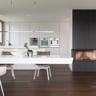 Offene, Zweizeilige, Große Moderne Küche mit flächenbündigen Schrankfronten, weißen Schränken, Küchengeräten aus Edelstahl, dunklem Holzboden, braunem Boden, Halbinsel und weißer Arbeitsplatte in Stuttgart