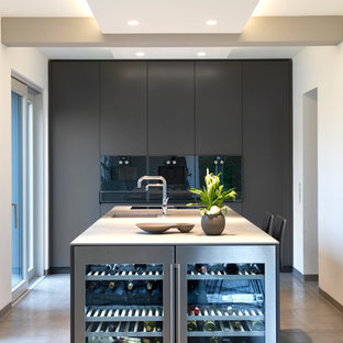 Photo of a large contemporary galley open plan kitchen in Other with an integrated sink, flat-panel cabinets, grey cabinets, stainless steel benchtops, black appliances, cement tiles, with island, beige floor and white benchtop.
