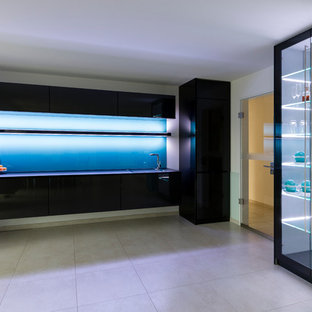 Mid-sized contemporary single-wall open plan kitchen in Hamburg with glass-front cabinets, grey cabinets, glass benchtops, green splashback, glass sheet splashback, panelled appliances, cement tiles, an integrated sink, no island and grey floor.