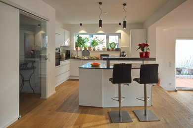Zweizeilige, Mittelgroße Moderne Wohnküche mit hellem Holzboden und Kücheninsel in Hannover