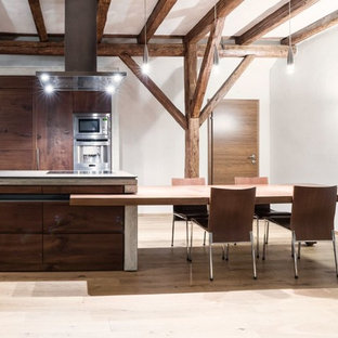 Esempio di una grande cucina abitabile minimal con ante lisce, ante in legno bruno, elettrodomestici in acciaio inossidabile, parquet chiaro, penisola e top in cemento