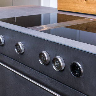 Inspiration for a large contemporary single-wall open plan kitchen in Frankfurt with flat-panel cabinets, black cabinets, concrete benchtops, yellow splashback, stainless steel appliances, with island and grey benchtop.