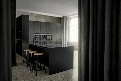 Inspiration för avskilda, stora industriella svart l-kök, med en integrerad diskho, släta luckor, svarta skåp, svarta vitvaror, en halv köksö och grått golv