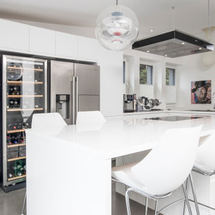 Mittelgroße Moderne Küchenbar in L-Form mit Einbauwaschbecken, flächenbündigen Schrankfronten, weißen Schränken, Küchengeräten aus Edelstahl, Kücheninsel, grauem Boden und weißer Arbeitsplatte in Dortmund