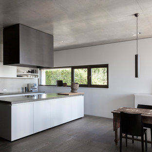 Zweizeilige, Große Moderne Wohnküche mit Einbauwaschbecken, flächenbündigen Schrankfronten, weißen Schränken, Küchenrückwand in Grau, Betonboden, Kücheninsel und grauem Boden in Stuttgart