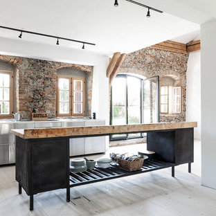 Offene Landhaus Küche mit flächenbündigen Schrankfronten, Edelstahlfronten, hellem Holzboden, Kücheninsel, beigem Boden und weißer Arbeitsplatte in München