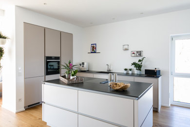Offene, Mittelgroße Moderne Küche in L-Form mit flächenbündigen Schrankfronten und Kücheninsel in Stuttgart