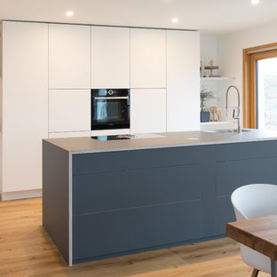 Inspiration for a large modern single-wall open plan kitchen in Stuttgart with flat-panel cabinets, white cabinets, laminate benchtops, with island, blue benchtop, an integrated sink, medium hardwood floors and brown floor.