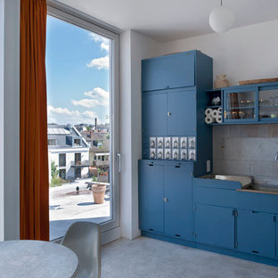 Einzeilige, Kleine Moderne Wohnküche ohne Insel mit Doppelwaschbecken, blauen Schränken, Küchenrückwand in Grau, Betonboden, flächenbündigen Schrankfronten, Rückwand aus Steinfliesen und Elektrogeräten mit Frontblende in Frankfurt am Main