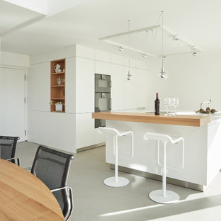 Einzeilige, Mittelgroße Moderne Wohnküche mit flächenbündigen Schrankfronten, weißen Schränken, schwarzen Elektrogeräten, Vinylboden, Kücheninsel, grauem Boden und weißer Arbeitsplatte in Stuttgart