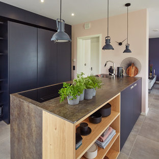 Offene, Zweizeilige, Mittelgroße Moderne Küche mit Einbauwaschbecken, flächenbündigen Schrankfronten, grauen Schränken, Küchenrückwand in Grau, schwarzen Elektrogeräten, Kücheninsel, grauem Boden und brauner Arbeitsplatte in Sonstige