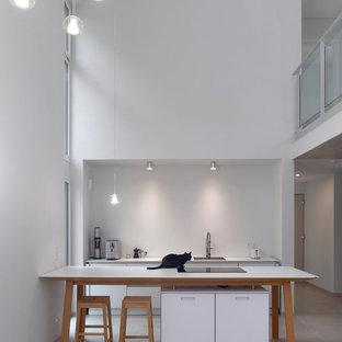 Moderne Küche mit Waschbecken, flächenbündigen Schrankfronten, weißen Schränken, Küchenrückwand in Weiß, Betonboden, Halbinsel, grauem Boden und weißer Arbeitsplatte in Sonstige