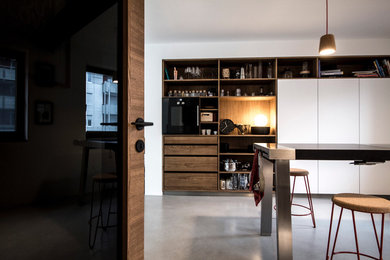 Moderne Küche mit flächenbündigen Schrankfronten, Betonboden und Kücheninsel in München