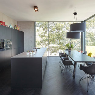 Zweizeilige, Mittelgroße Moderne Wohnküche mit flächenbündigen Schrankfronten, schwarzen Schränken, schwarzen Elektrogeräten, dunklem Holzboden, zwei Kücheninseln, schwarzem Boden und schwarzer Arbeitsplatte in Köln