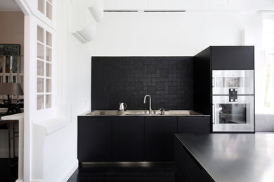 Design ideas for a large modern single-wall enclosed kitchen in Hamburg with flat-panel cabinets, black cabinets, black splashback, stainless steel appliances, black floors, multiple islands and black worktops.