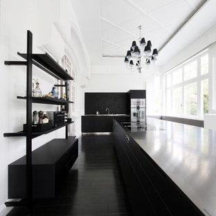Geschlossene, Einzeilige, Große Moderne Küche mit flächenbündigen Schrankfronten, schwarzen Schränken, Küchenrückwand in Schwarz, Küchengeräten aus Edelstahl, zwei Kücheninseln, schwarzem Boden und schwarzer Arbeitsplatte in Hamburg
