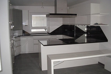 Geräumige Moderne Küche mit flächenbündigen Schrankfronten, weißen Schränken, Granit-Arbeitsplatte, Rückwand aus Spiegelfliesen und Küchengeräten aus Edelstahl in München