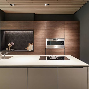Zweizeilige, Mittelgroße Moderne Wohnküche mit Unterbauwaschbecken, flächenbündigen Schrankfronten, dunklen Holzschränken, Küchenrückwand in Schwarz, Rückwand aus Zementfliesen, Küchengeräten aus Edelstahl, Kücheninsel, grauem Boden und grauer Arbeitsplatte in Stuttgart