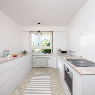 Zweizeilige, Mittelgroße Moderne Küche mit Einbauwaschbecken, flächenbündigen Schrankfronten, weißen Schränken, Arbeitsplatte aus Holz, Küchenrückwand in Weiß, Elektrogeräten mit Frontblende, beigem Boden und beiger Arbeitsplatte in Sonstige