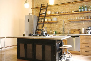 Large industrial single-wall open plan kitchen in Berlin with beaded cabinets, medium wood cabinets, stainless steel appliances, light hardwood flooring and an island.