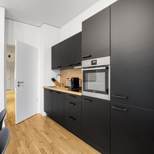 Einzeilige, Mittelgroße Moderne Küche ohne Insel mit Einbauwaschbecken, flächenbündigen Schrankfronten, schwarzen Schränken, Küchenrückwand in Beige, Elektrogeräten mit Frontblende, beigem Boden und beiger Arbeitsplatte in Berlin