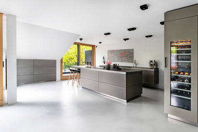 Offene, Geräumige Moderne Küche in L-Form mit Edelstahl-Arbeitsplatte, Betonboden, Kücheninsel und grauem Boden in Sonstige
