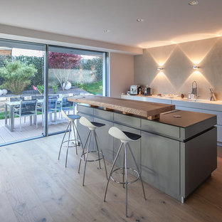 Design ideas for a large contemporary galley open plan kitchen in Munich with an integrated sink, flat-panel cabinets, white cabinets, wood benchtops, grey splashback, slate splashback, stainless steel appliances, light hardwood floors, with island and brown floor.