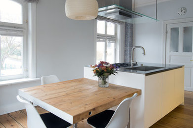 Offene, Mittelgroße Moderne Küche mit integriertem Waschbecken, flächenbündigen Schrankfronten, weißen Schränken, Kücheninsel, beigem Boden, grauer Arbeitsplatte und braunem Holzboden in Hamburg