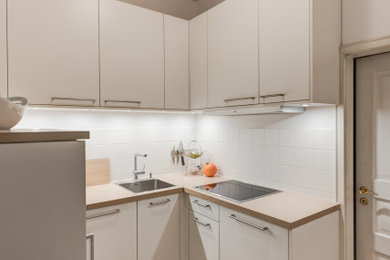 Geschlossene, Kleine Moderne Küche ohne Insel in U-Form mit flächenbündigen Schrankfronten, weißen Schränken, Küchengeräten aus Edelstahl und braunem Holzboden in München