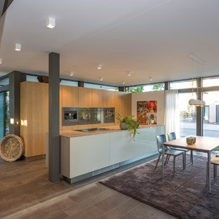 Zweizeilige, Große Moderne Wohnküche mit flächenbündigen Schrankfronten, hellbraunen Holzschränken, Küchengeräten aus Edelstahl, Halbinsel, grauem Boden, beiger Arbeitsplatte, Waschbecken, Edelstahl-Arbeitsplatte, Küchenrückwand in Weiß, Rückwand aus Holz und Keramikboden in Sonstige