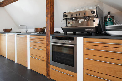Modelo de cocina contemporánea de tamaño medio con electrodomésticos de acero inoxidable, suelo de pizarra y suelo negro