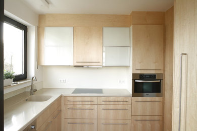 Moderne Küche in L-Form mit hellen Holzschränken und Granit-Arbeitsplatte in Sonstige