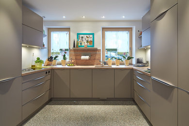 Mittelgroße Moderne Küche mit Unterbauwaschbecken, flächenbündigen Schrankfronten, grauen Schränken, Küchenrückwand in Weiß, buntem Boden und Arbeitsplatte aus Holz in München