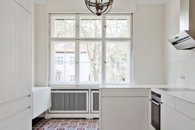 Foto de cocina contemporánea de tamaño medio cerrada con armarios con paneles lisos, puertas de armario blancas, salpicadero blanco, península y electrodomésticos con paneles