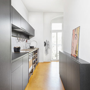 Esempio di una piccola cucina lineare design chiusa con lavello da incasso, ante lisce, ante grigie, paraspruzzi bianco, elettrodomestici in acciaio inossidabile, nessuna isola e pavimento giallo
