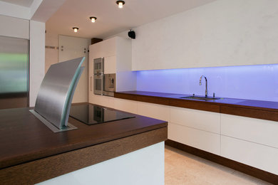 Offene, Große Moderne Küche mit integriertem Waschbecken, flächenbündigen Schrankfronten, Arbeitsplatte aus Holz, Glasrückwand und Kücheninsel in Hamburg