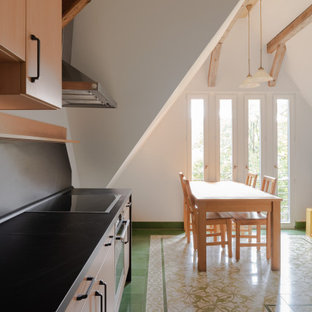 Design ideas for a large country galley eat-in kitchen in Other with an integrated sink, flat-panel cabinets, light wood cabinets, solid surface benchtops, black splashback, slate splashback, stainless steel appliances, porcelain floors, no island, green floor and black benchtop.
