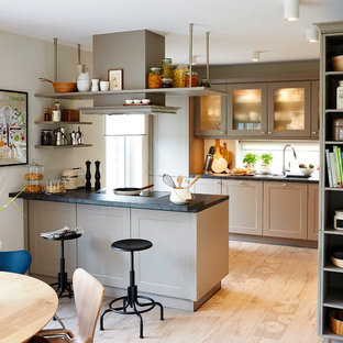 Offene, Mittelgroße, Zweizeilige Moderne Küchenbar mit schwarzer Arbeitsplatte, Schrankfronten im Shaker-Stil, grauen Schränken, Halbinsel, beigem Boden, Einbauwaschbecken, Rückwand-Fenster und hellem Holzboden in Hamburg
