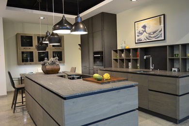 Cette image montre une cuisine ouverte parallèle design de taille moyenne avec un plan de travail en quartz, une crédence grise, un électroménager en acier inoxydable, îlot et un évier encastré.