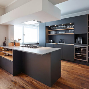 Zweizeilige, Mittelgroße Moderne Wohnküche mit Einbauwaschbecken, flächenbündigen Schrankfronten, schwarzen Schränken, Quarzit-Arbeitsplatte, Küchenrückwand in Schwarz, Küchengeräten aus Edelstahl, dunklem Holzboden, zwei Kücheninseln und braunem Boden in Düsseldorf