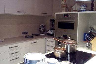 Offene Moderne Küche in U-Form mit weißen Schränken, Küchengeräten aus Edelstahl und Halbinsel in Stuttgart