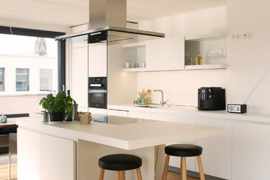 Offene, Einzeilige, Große Moderne Küche mit Laminat-Arbeitsplatte, schwarzen Elektrogeräten, hellem Holzboden und Kücheninsel in Sonstige