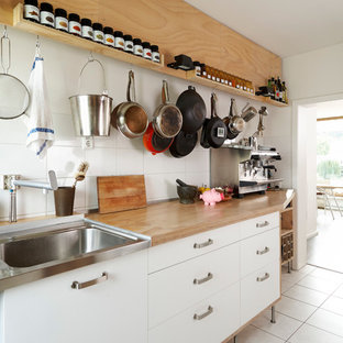 Photo of an eclectic kitchen in Cologne with flat-panel cabinets, white cabinets, wood benchtops, a drop-in sink, white splashback and ceramic splashback.