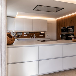 Mittelgroße Moderne Küche in U-Form mit Unterbauwaschbecken, flächenbündigen Schrankfronten, weißen Schränken, Küchenrückwand in Braun, Rückwand aus Holz, Elektrogeräten mit Frontblende, Halbinsel, braunem Boden und weißer Arbeitsplatte in Nürnberg