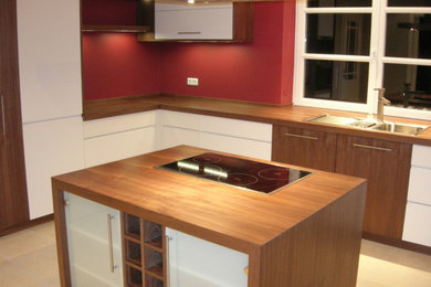 Imagen de cocina actual abierta con armarios con paneles lisos, encimera de madera y una isla