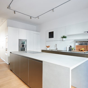 Mittelgroße Moderne Wohnküche in L-Form mit flächenbündigen Schrankfronten, Küchenrückwand in Weiß, Glasrückwand, Küchengeräten aus Edelstahl, braunem Holzboden, Kücheninsel, braunem Boden, weißer Arbeitsplatte, Doppelwaschbecken und weißen Schränken in Hamburg