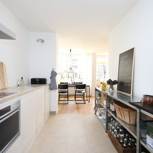 Offene, Zweizeilige, Mittelgroße Moderne Küche ohne Insel mit flächenbündigen Schrankfronten, weißen Schränken, Arbeitsplatte aus Holz, Küchengeräten aus Edelstahl, beigem Boden und beiger Arbeitsplatte in München