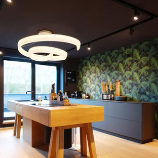 Zweizeilige, Große Moderne Küche mit Einbauwaschbecken, flächenbündigen Schrankfronten, schwarzen Schränken, bunter Rückwand, Kücheninsel, braunem Boden, schwarzer Arbeitsplatte und Tapetendecke in Hannover