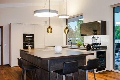 Moderne Wohnküche in L-Form mit schwarzen Elektrogeräten und Kücheninsel in Sonstige